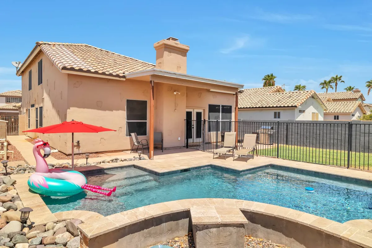 A playful backyard pool scene featuring a flamingo float, red umbrella, and lounge chairs. The image evokes a fun, relaxing atmosphere for swimming, sunbathing, and socializing—perfect for unwinding after a day of exploring.