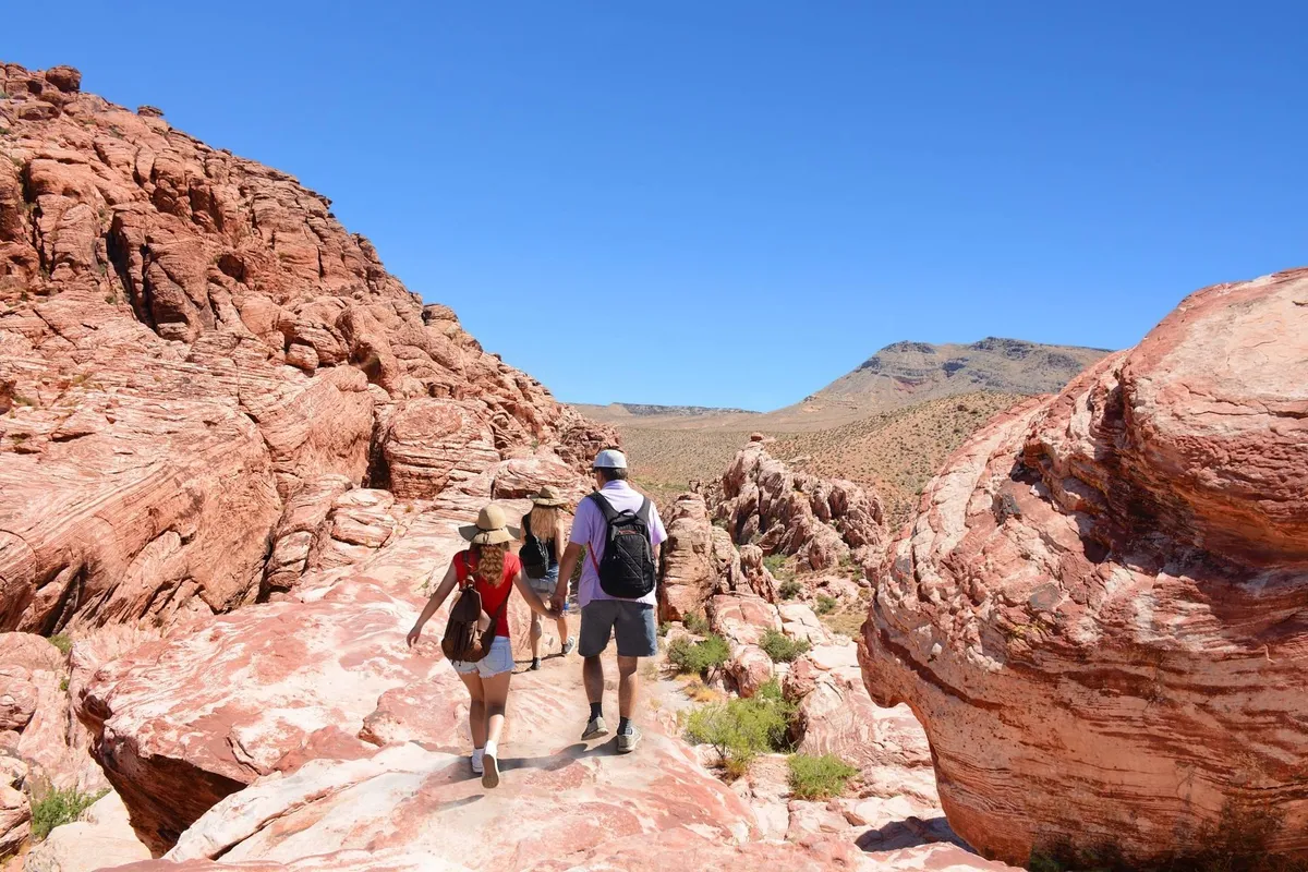 Set against a vivid blue sky, this image shows hikers exploring rugged rock formations along a scenic trail. The sense of adventure and connection to nature is palpable, ideal for families seeking outdoor activities.