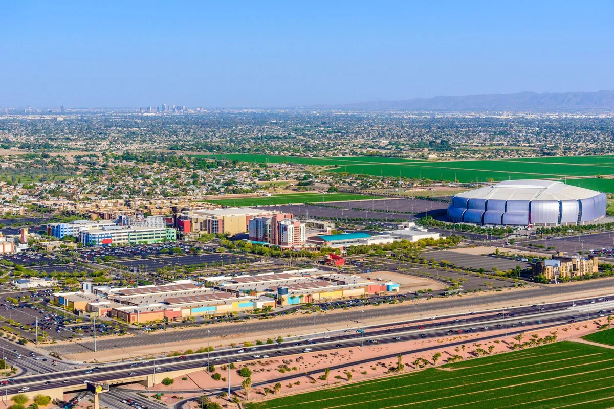 This exterior image captures a large stadium surrounded by urban development, highways, and agricultural fields. The energetic scene hints at sports events, shopping, dining, and vibrant community gatherings—all activities families can enjoy nearby.